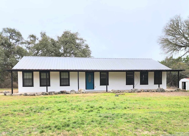 view of front facade featuring a front yard, covered porch, metal roof, and stucco siding