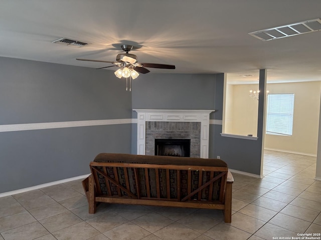 living area with a brick fireplace, ceiling fan, light tile patterned floors, and visible vents