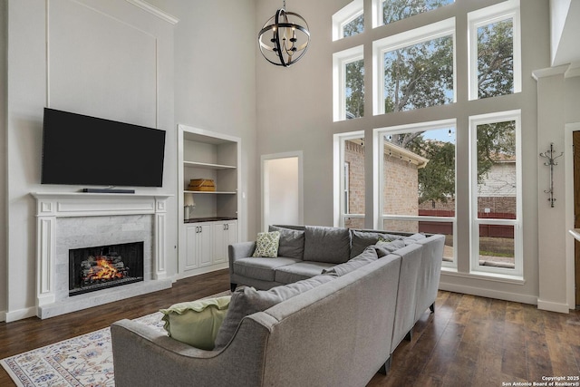 living area with built in features, a wealth of natural light, and dark wood finished floors