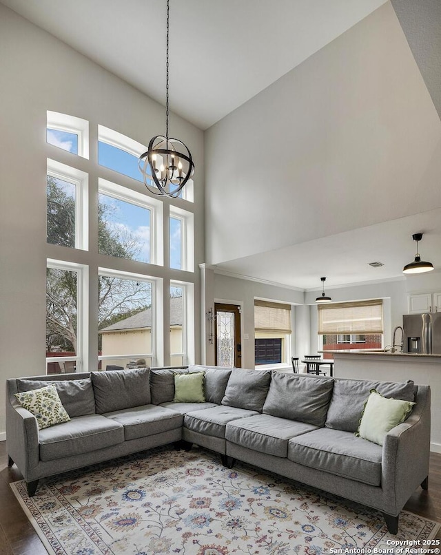 living area featuring dark wood-style floors, a high ceiling, and a chandelier