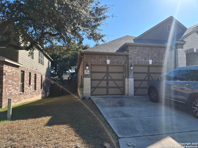 view of side of property featuring a shingled roof, concrete driveway, brick siding, and an attached garage