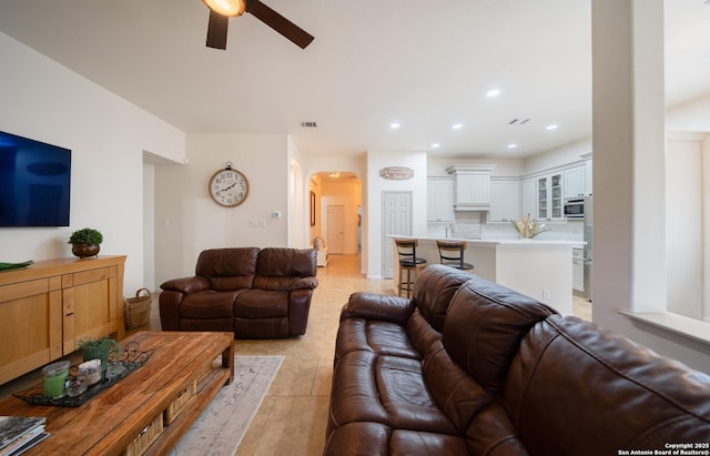 living room with arched walkways, light tile patterned floors, recessed lighting, visible vents, and a ceiling fan