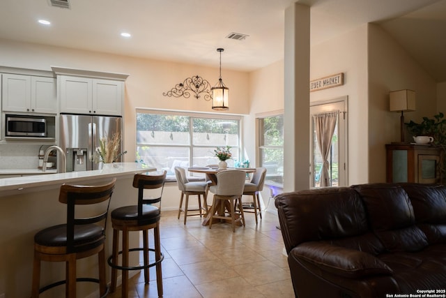 kitchen featuring a breakfast bar area, light countertops, visible vents, hanging light fixtures, and appliances with stainless steel finishes