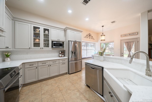 kitchen with visible vents, appliances with stainless steel finishes, decorative light fixtures, a sink, and light tile patterned flooring