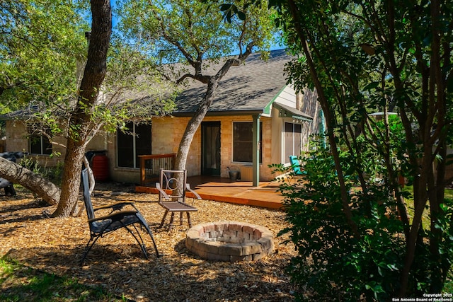 rear view of property featuring an outdoor fire pit and a shingled roof