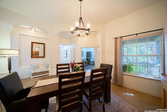 dining room with arched walkways, baseboards, and an inviting chandelier