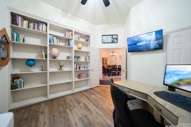 office with ceiling fan with notable chandelier and wood finished floors