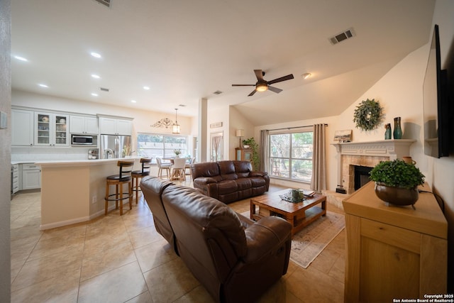 living area with light tile patterned floors, recessed lighting, visible vents, a tiled fireplace, and vaulted ceiling