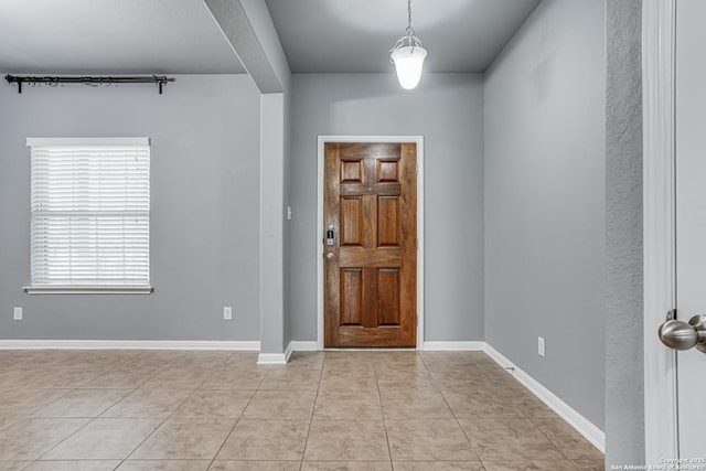 foyer featuring light tile patterned flooring and baseboards