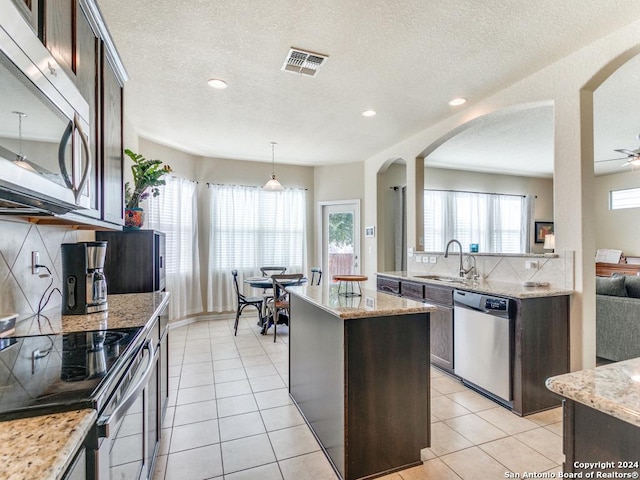 kitchen featuring appliances with stainless steel finishes, light tile patterned flooring, a sink, and dark brown cabinetry