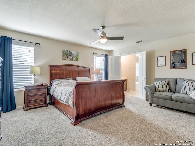 carpeted bedroom with ensuite bath, visible vents, ceiling fan, and a textured ceiling