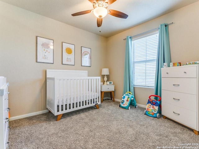 carpeted bedroom with a nursery area, ceiling fan, and baseboards