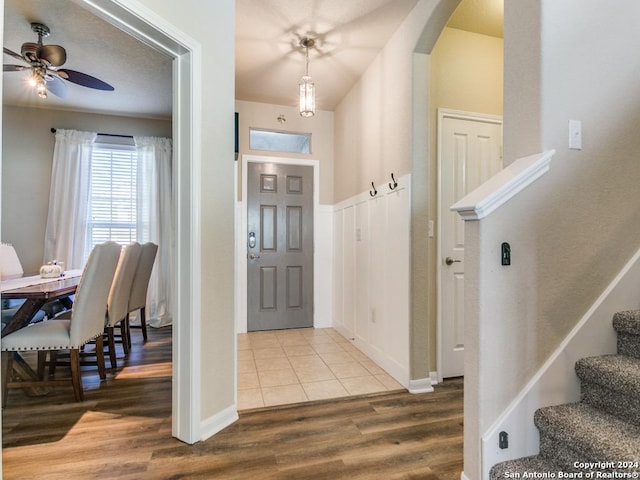 foyer with arched walkways, ceiling fan, wood finished floors, and stairs