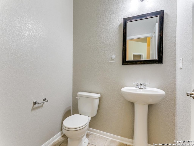 half bath with tile patterned flooring, toilet, and baseboards