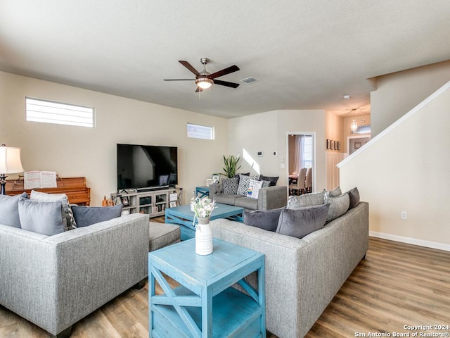 living room with ceiling fan, wood finished floors, visible vents, and baseboards