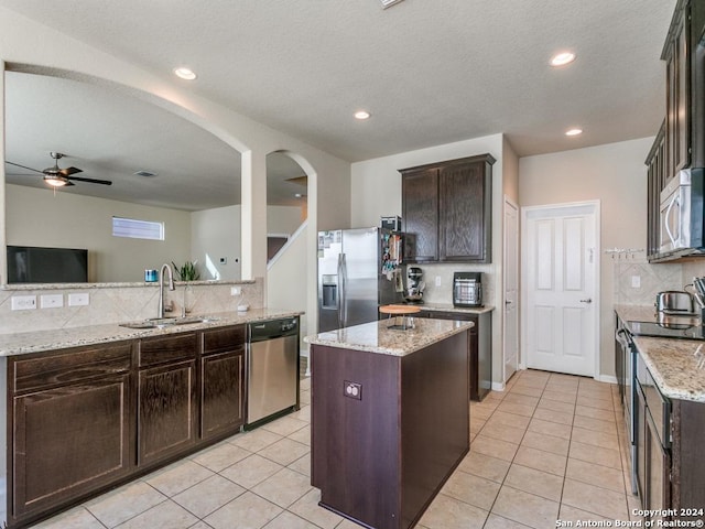 kitchen with appliances with stainless steel finishes, light tile patterned flooring, a sink, and dark brown cabinets