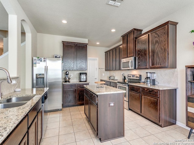 kitchen featuring light tile patterned floors, stainless steel appliances, a sink, visible vents, and decorative backsplash