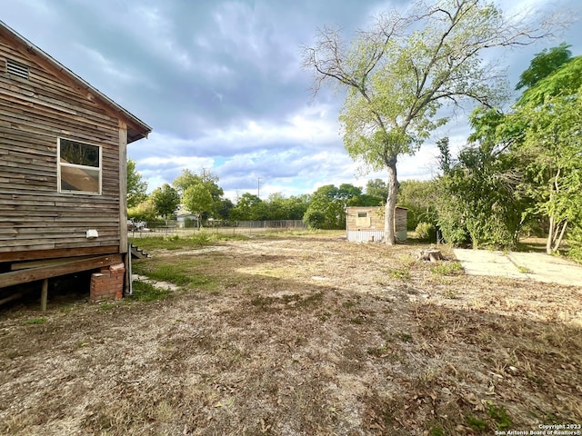 view of yard with an outbuilding, a shed, and fence