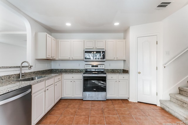 kitchen featuring light tile patterned floors, stone countertops, stainless steel appliances, a sink, and visible vents