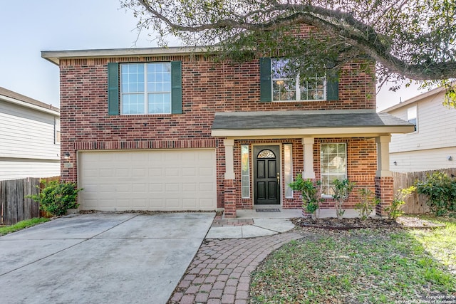 traditional-style house with driveway, brick siding, an attached garage, and fence