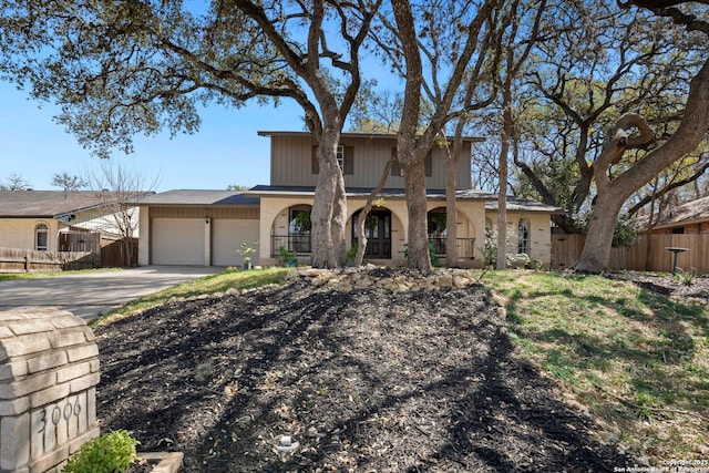 view of front of property featuring covered porch, driveway, an attached garage, and fence