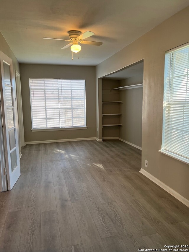 unfurnished bedroom with multiple windows, baseboards, and dark wood finished floors