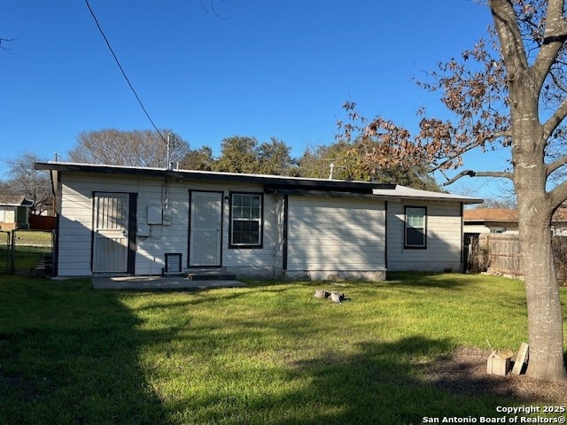 rear view of house with a yard and fence