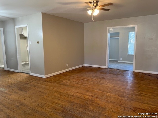 empty room with wood finished floors, a ceiling fan, and baseboards