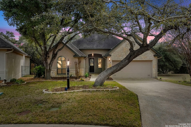 view of front of property with driveway, stone siding, an attached garage, a front yard, and stucco siding