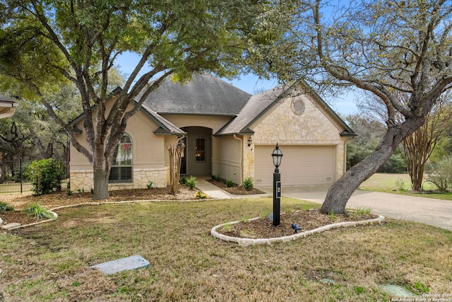 french country inspired facade with an attached garage, a shingled roof, stone siding, driveway, and a front lawn