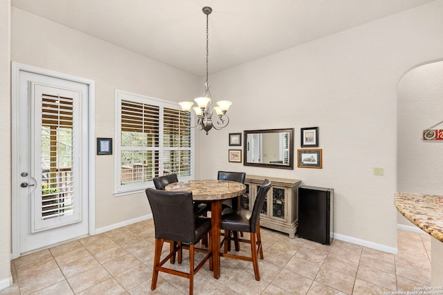 dining area featuring light tile patterned floors, baseboards, and an inviting chandelier