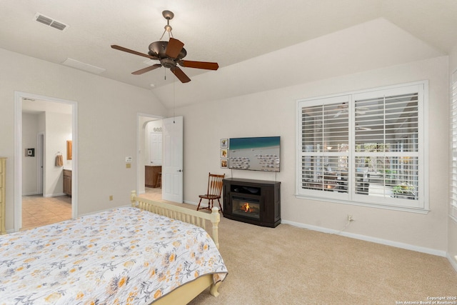 bedroom with baseboards, visible vents, light colored carpet, lofted ceiling, and a glass covered fireplace