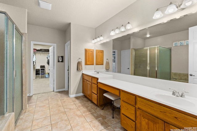 full bath featuring a textured ceiling, vanity, a spacious closet, tile patterned floors, and a stall shower