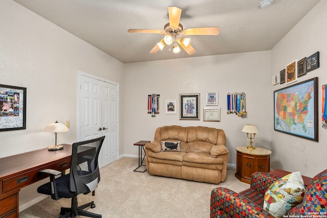 office space featuring light carpet, ceiling fan, baseboards, and a textured ceiling