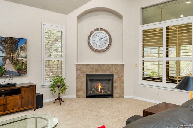 carpeted living area featuring a healthy amount of sunlight, baseboards, and a tile fireplace