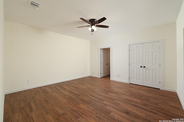 unfurnished bedroom with a ceiling fan, visible vents, baseboards, a closet, and dark wood finished floors