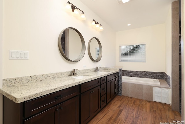 full bathroom with visible vents, a sink, a bath, and wood finished floors