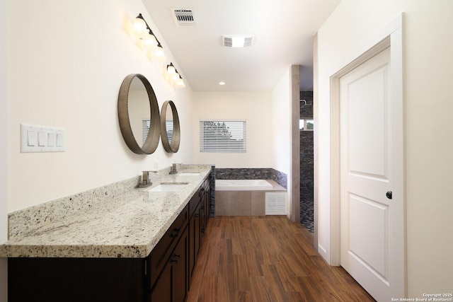 full bathroom with a bath, visible vents, wood finished floors, and vanity