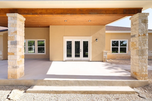 property entrance featuring french doors, a patio, stucco siding, a shingled roof, and stone siding