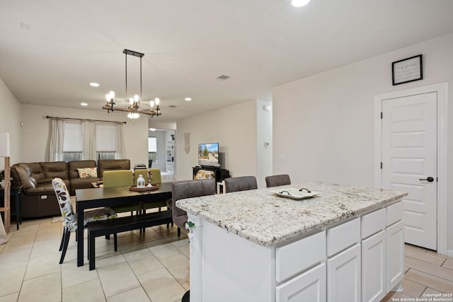 kitchen featuring pendant lighting, visible vents, open floor plan, white cabinets, and a kitchen island