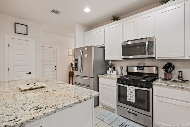 kitchen featuring tasteful backsplash, visible vents, white cabinets, light stone counters, and stainless steel appliances