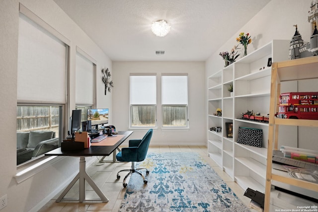 office space featuring baseboards, visible vents, a textured ceiling, and light tile patterned flooring