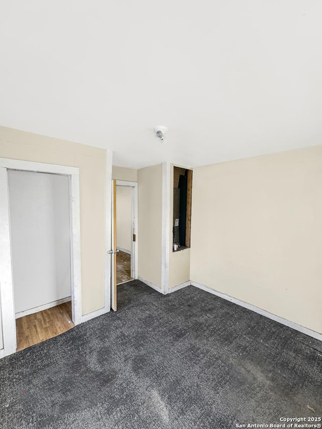 interior space with dark carpet and baseboards