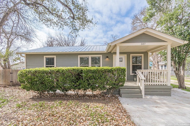 view of front of house with covered porch, metal roof, and fence