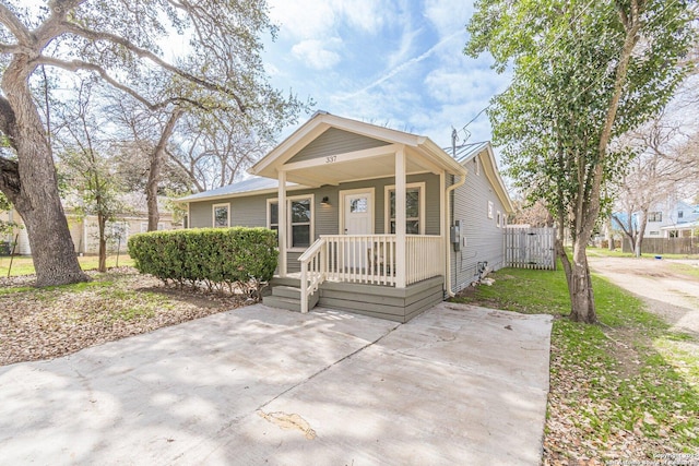 view of front of house with covered porch, metal roof, and fence