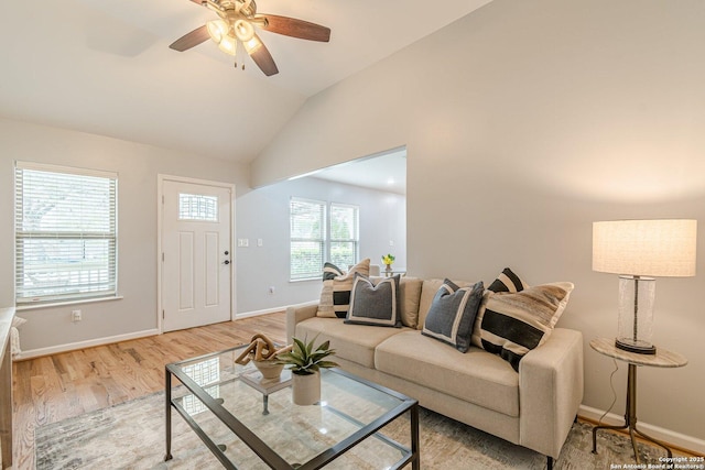 living area with light wood finished floors, ceiling fan, baseboards, and vaulted ceiling