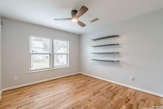 spare room featuring visible vents, ceiling fan, baseboards, and wood finished floors