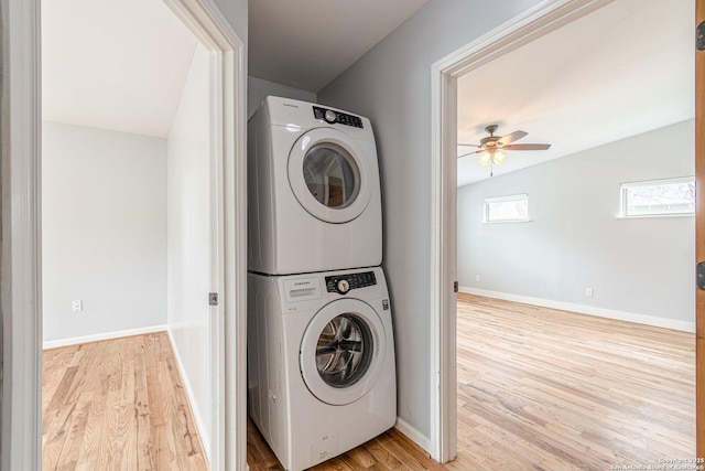 laundry area featuring laundry area, light wood-style flooring, baseboards, and stacked washer / dryer