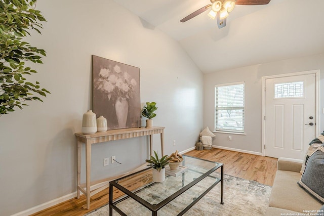 living room featuring ceiling fan, vaulted ceiling, baseboards, and wood finished floors