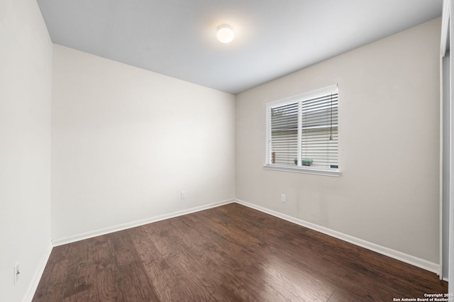 spare room with dark wood-style floors and baseboards